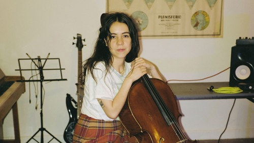 Artist Mabe Fratti, sitting in a chair with her Cello